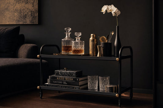 Black bar cart Australia — matte black bar cart with gold accents styled with crystal decanters and whisky glasses in a dark luxe interior