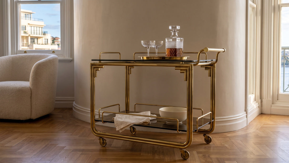 An Art Deco brass and smoked-glass bar trolley with cut-crystal glassware in a Potts Point apartment living room