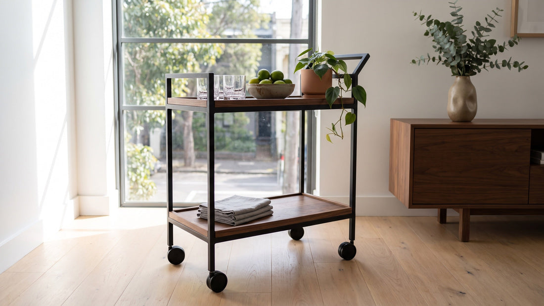 A slim black and walnut bar cart holding glassware beside a walnut sideboard in a Melbourne terrace dining room