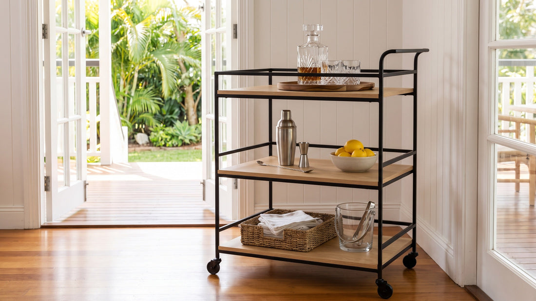 A three-tier black iron and oak bar cart with each shelf neatly arranged, in the living room of a Brisbane Queenslander