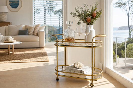 Drinks trolley Newcastle Australia — gold two-tier bar cart in a bright coastal Australian home with natural light, crystal decanter and native botanicals