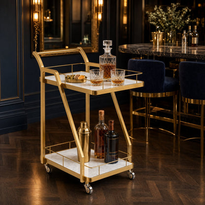The Mosman Two-Tier Gold Marble-Look Service Cart featuring a striking Z-frame and white faux-marble shelves, styled with wine and glasses and day spas.