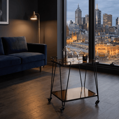 The Neutral Bay Two-Tier Glass Bar Cart by Royal Bar Carts showcasing black frame and brown glass shelves in a contemporary setting