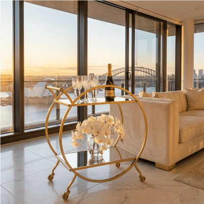The Orion Gold Circle Bar Cart’s elegant gold frame and glass shelves styled with contemporary barware by Royal Bar Carts.