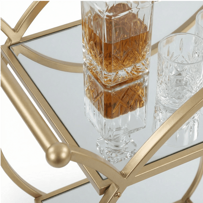 Close-up of The Orion Gold Circle Bar Cart’s elegant gold frame and glass shelves styled with cocktails and barware