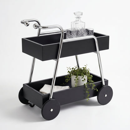 The Carlton Mid-Century Solid Wood Drinks Trolley in black on a white background — two black solid wood tray shelves, two ball-ended chrome-look handle arms and four large black timber disc wheels