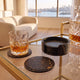 The Valet faux leather coasters in use on a gold bar cart in a Sydney apartment — two coasters out on the glass and four in the holder, one under a crystal tumbler